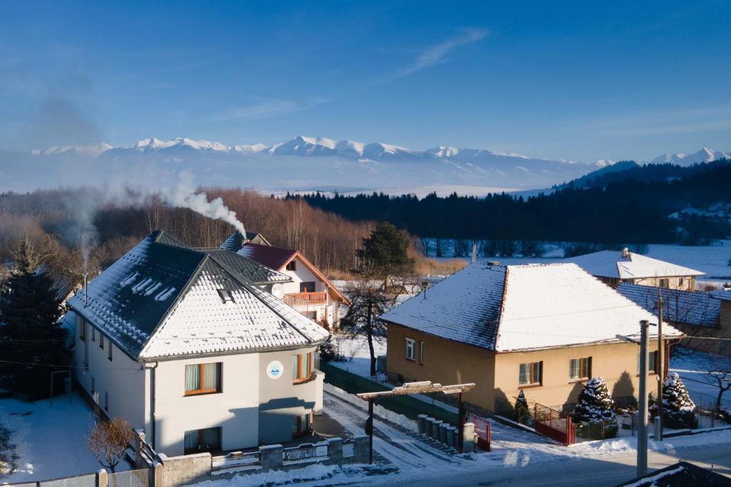 a group of buildings in the snow with mountains in the background at Penzión Pavčina Lehota in Pavčina Lehota