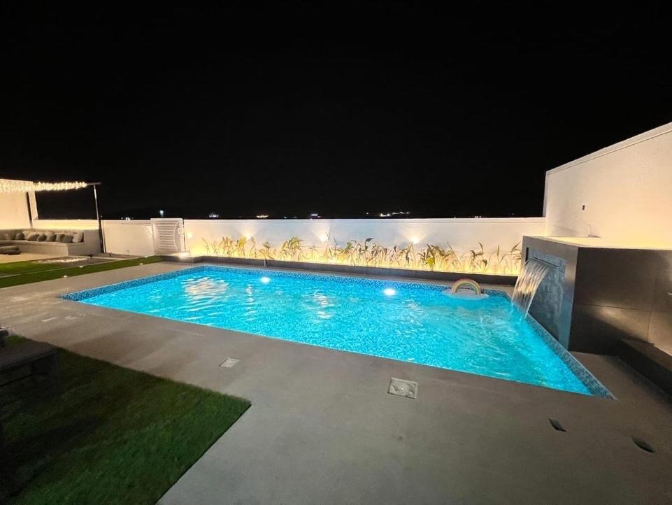 a large blue swimming pool at night at alsaif camp in Bidiyah