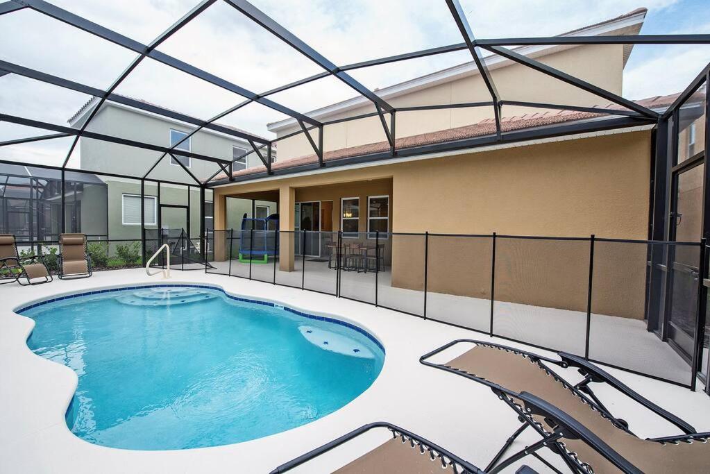 ein großer Pool mit Stühlen und ein Gebäude in der Unterkunft Cozy Solterra 5Bed45Bath-Disney-No Resort Fee in Davenport