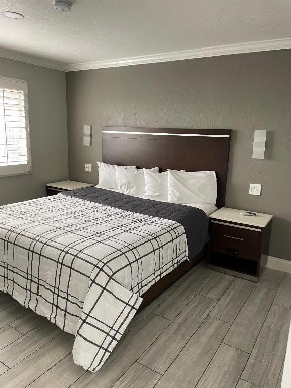 a bedroom with a large bed with a plaid blanket at Cabana Inn & Suites in Long Beach