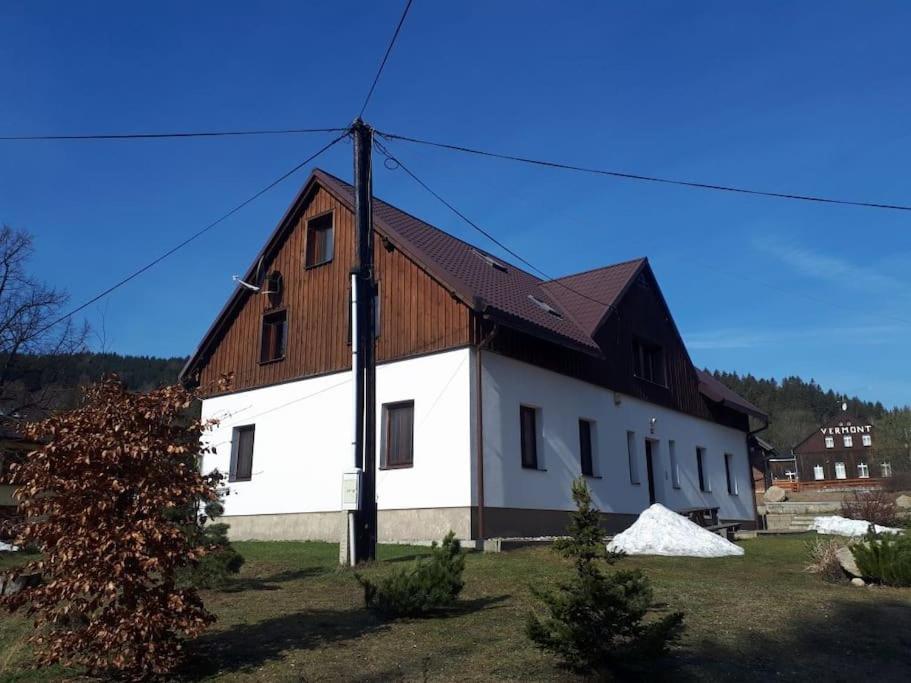 a large white building with a wooden roof at Byt 4+kk v klidné části obce Bedřichov in Bedřichov