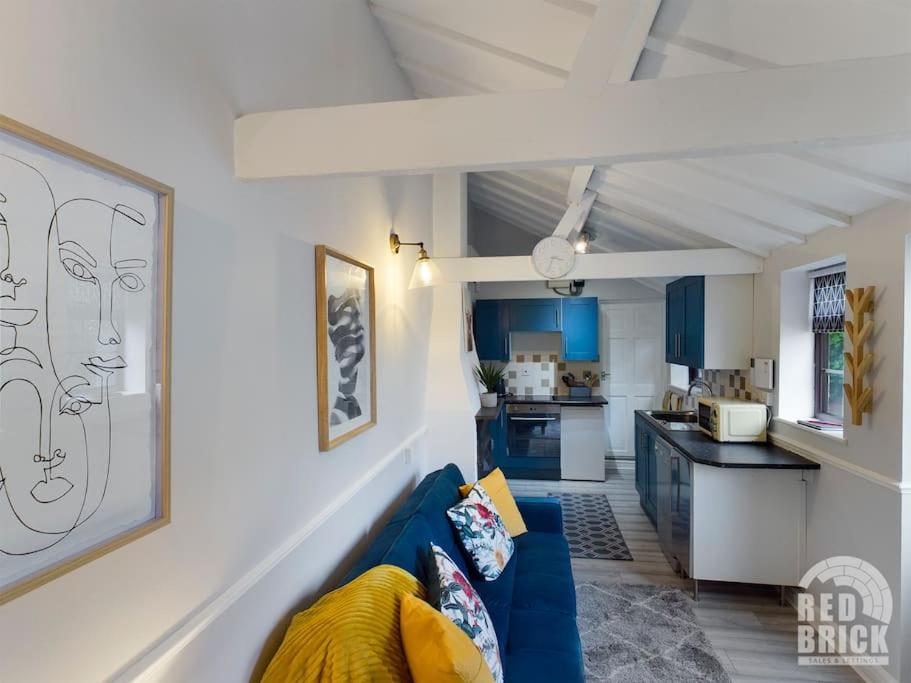 a living room with a blue couch and a kitchen at The Lodge at Pickford House NEC and B'Ham Airport, Coventry in Coventry