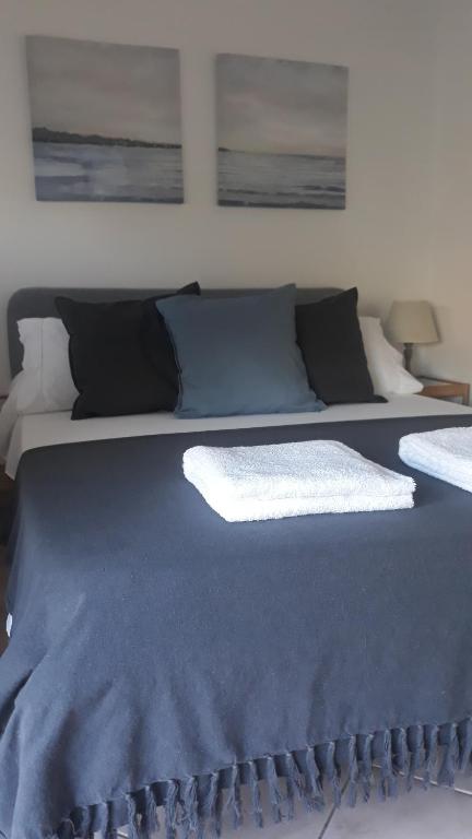 a large bed with blue sheets and pillows at Ostia Bed and Beach in Lido di Ostia