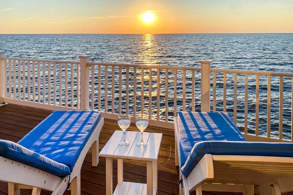 einen Balkon mit 2 Stühlen und einem Tisch mit Weingläsern in der Unterkunft Waterfront Sanctuary with Panoramic Bay Views! 