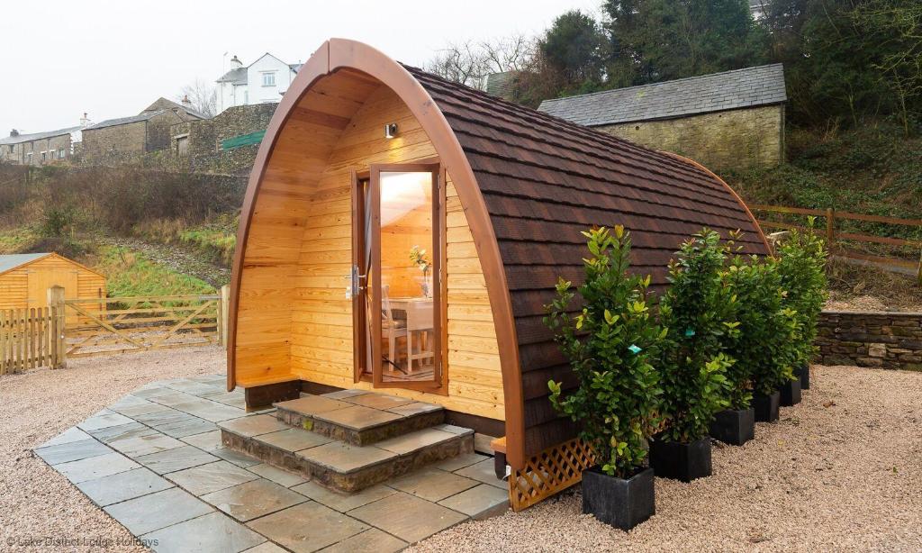 a small wooden house with stairs in a yard at Willow Tree Barn Pod in Kendal