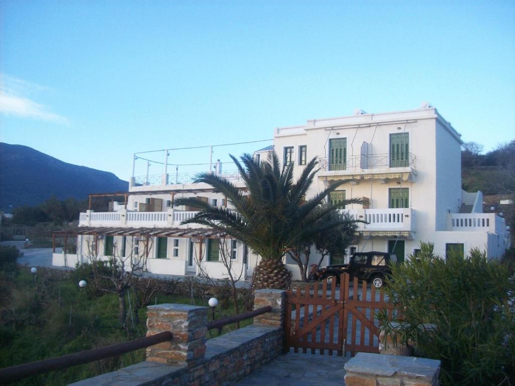 a white house with a palm tree in front of it at Vassiliki Studios in Andros