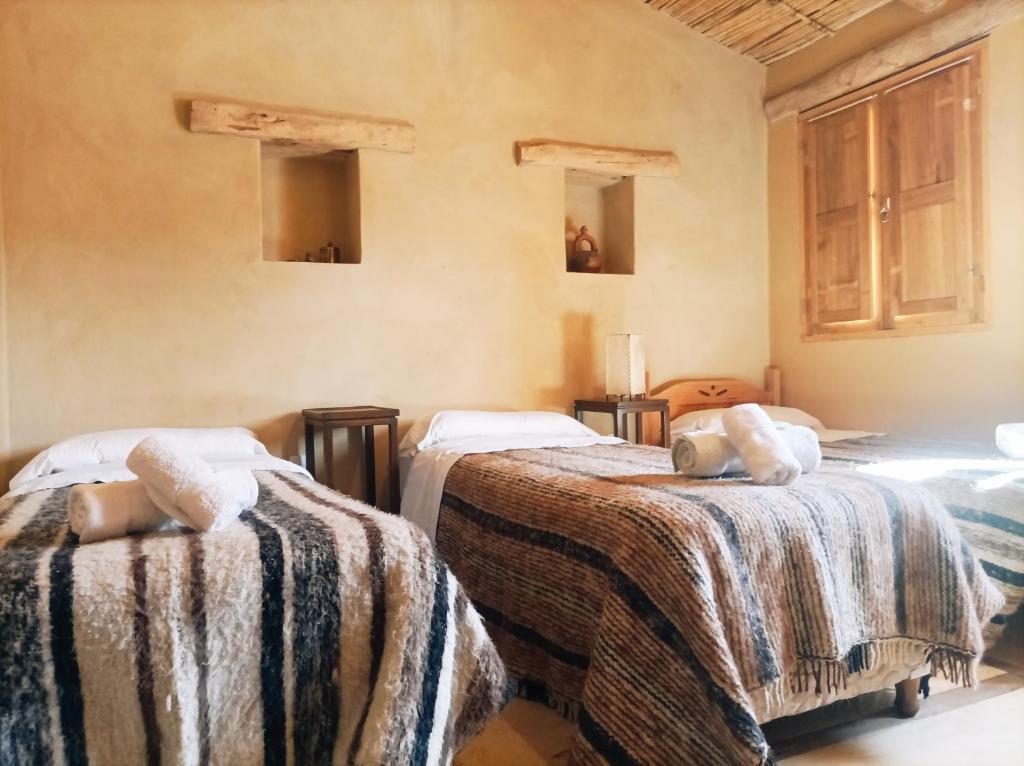 ein Zimmer mit 2 Betten und Decken darauf in der Unterkunft La Elegida in Tilcara