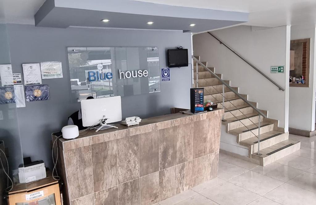 a blue house lobby with a desk and a staircase at Blue House Corferias in Bogotá