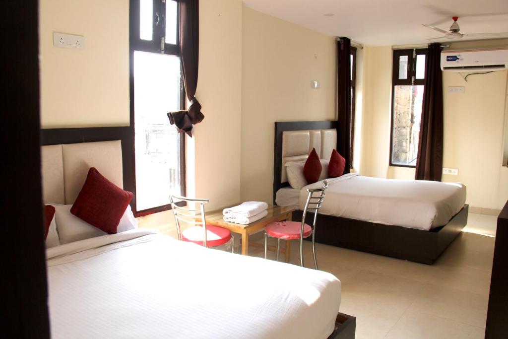 Tatsat Hostel في ريشيكيش: غرفة فندق بسريرين ومخدات حمراء