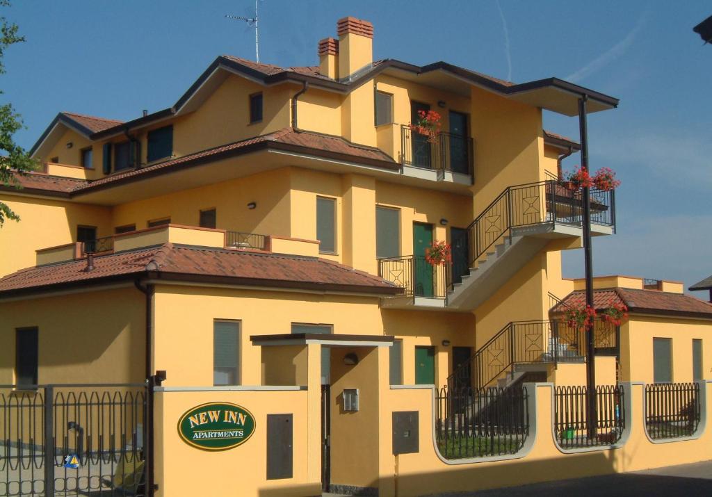 MedigliaにあるNew Inn Residenceの花の咲くバルコニー付きの大きな黄色の建物