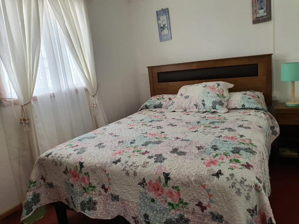 1 dormitorio con 1 cama con edredón de flores y ventana en Casa Quelita, en Punta de Choros