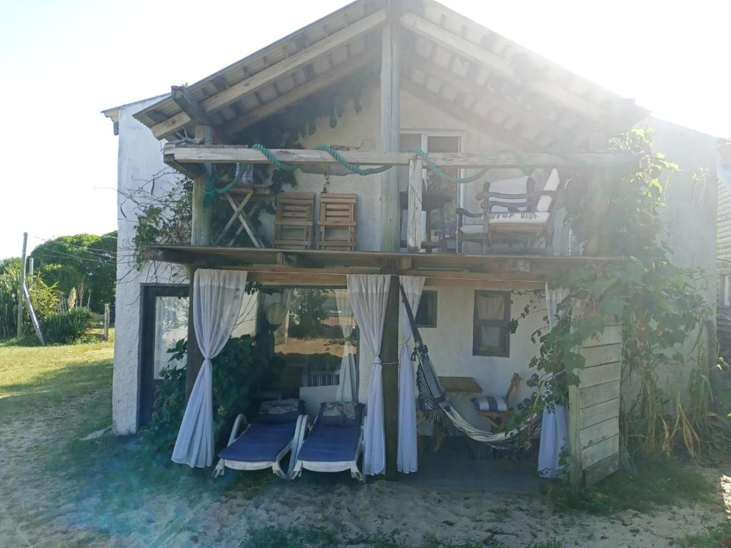 a house with chairs and a porch with the sun shining at Casa Vapahí in Barra de Valizas