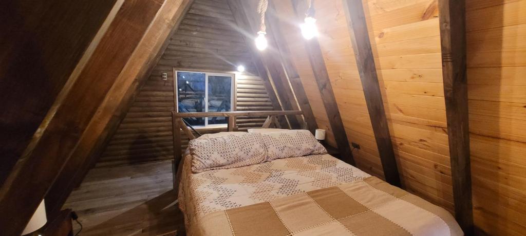 um pequeno quarto com uma cama num chalé de madeira em Cabaña Alpina para 2 en Puerto Varas em Puerto Varas