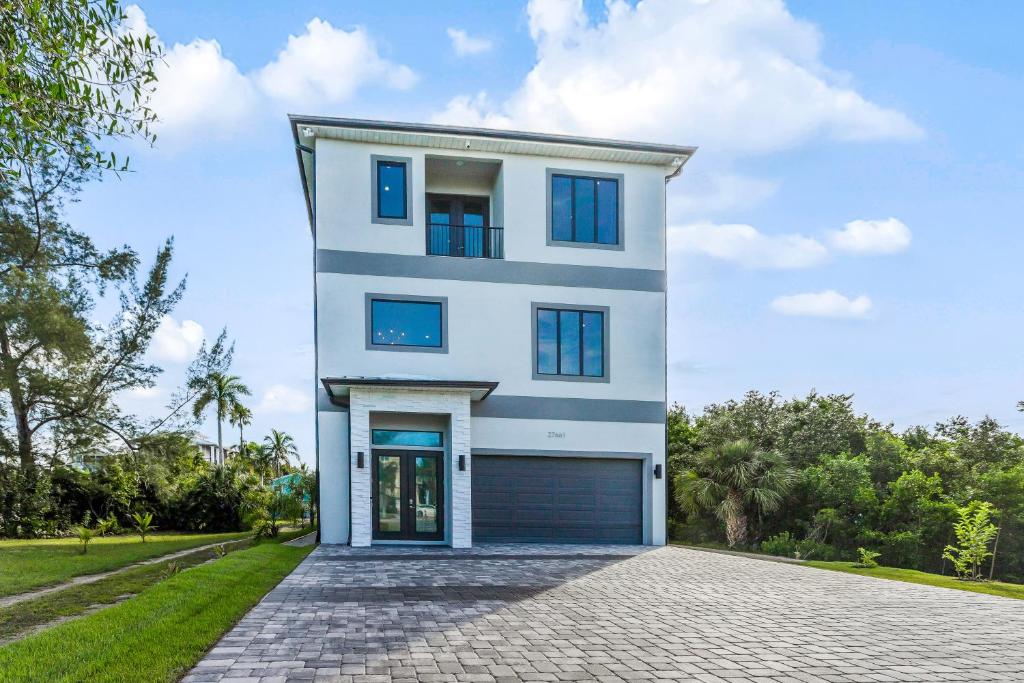 a white house with blue windows and a driveway at Modern Hickory Hideaway in Bonita Springs