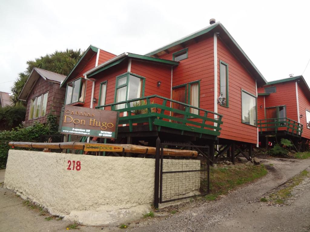 una casa roja con un cartel delante en Cabañas Don Hugo en Ancud