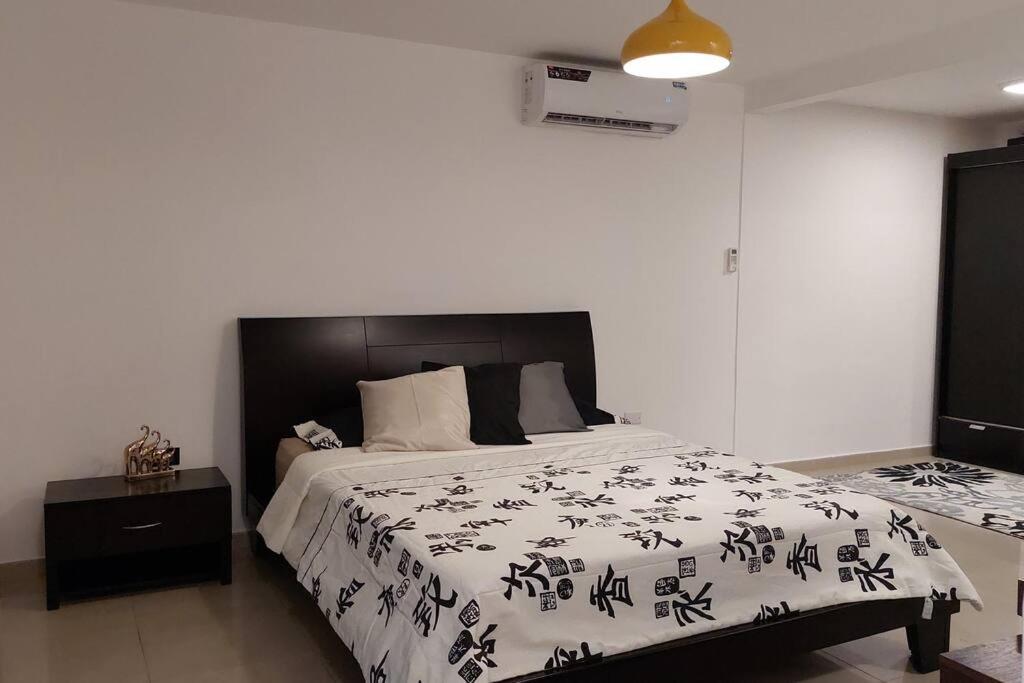 1 dormitorio con 1 cama con edredón blanco y negro en Acogedor y moderno loft con vista a la ciudad, en Guayaquil