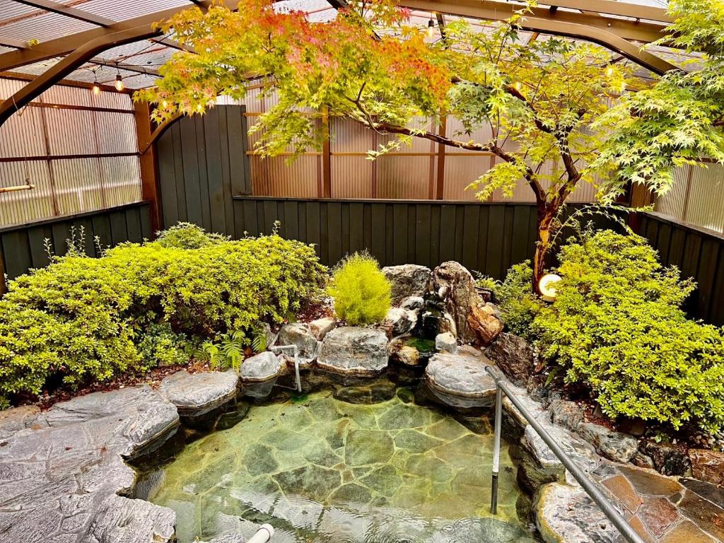 uma pequena piscina de água com uma árvore num jardim em 湯布院 ソナタ Yufuin Sonata em Yufu