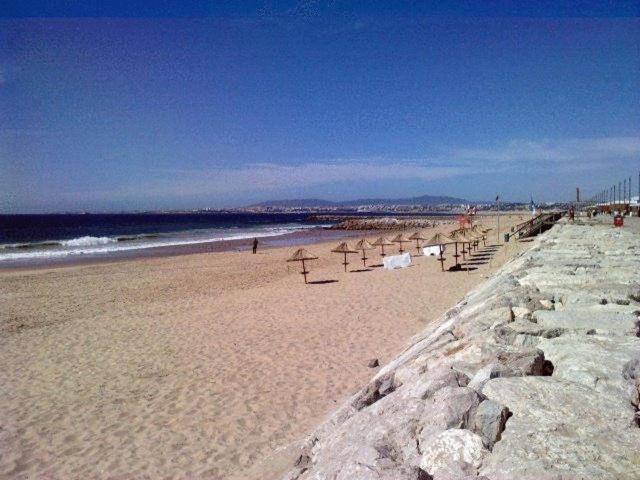 a beach with a row of umbrellas on the sand at Hotel Residencial Colibri in Costa da Caparica