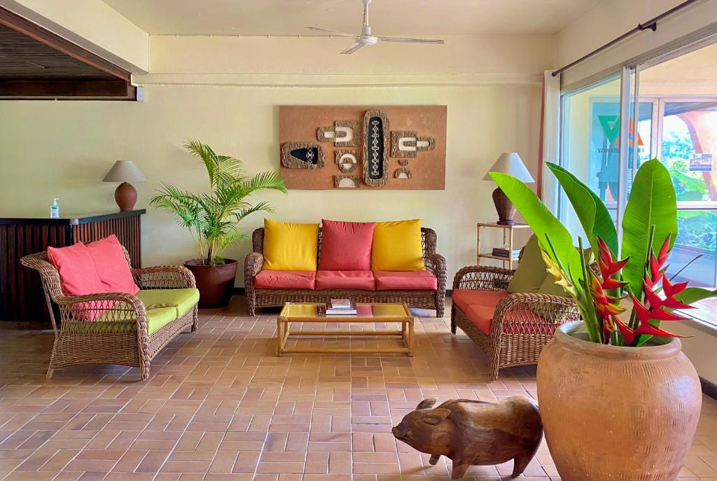 a living room with colorful couches and plants at Hotel Santo Vanuatu in Luganville