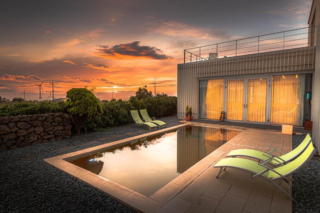 a house with a swimming pool with two lawn chairs at Boutique Pool Villa NAMIB in Jeju