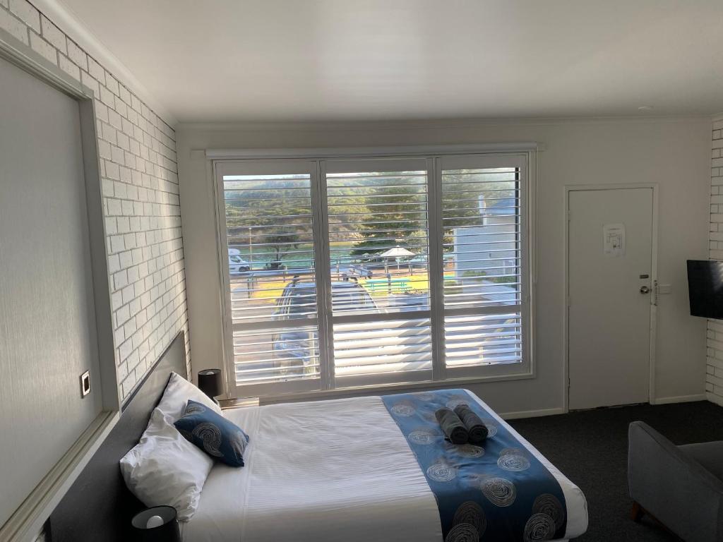 a bedroom with a bed and a large window at Southern Ocean Motor Inn in Port Campbell