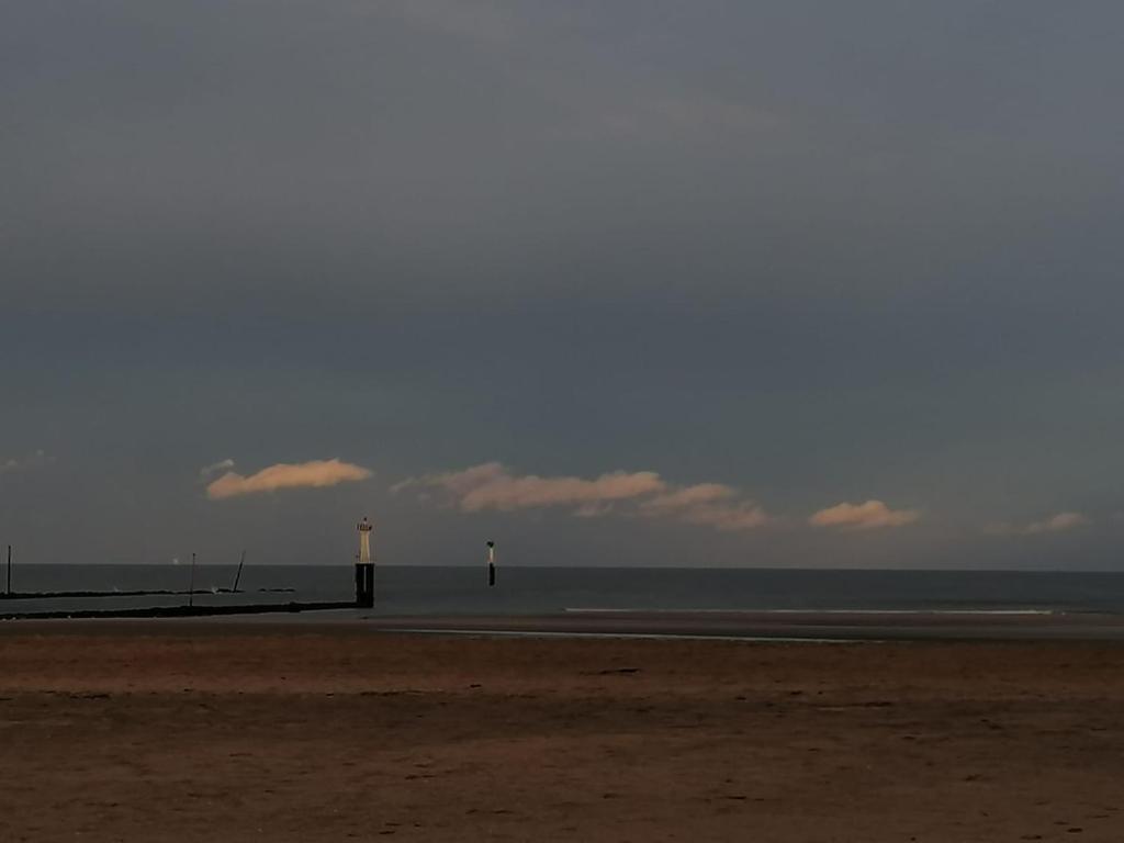 a beach with two light posts and the ocean at La Chambre du 21 in Trouville-sur-Mer