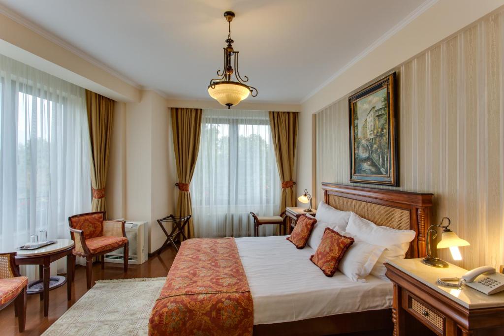 une chambre d'hôtel avec un lit, une table et des chaises dans l'établissement Vila Paris Boutique Hotel, à Bucarest