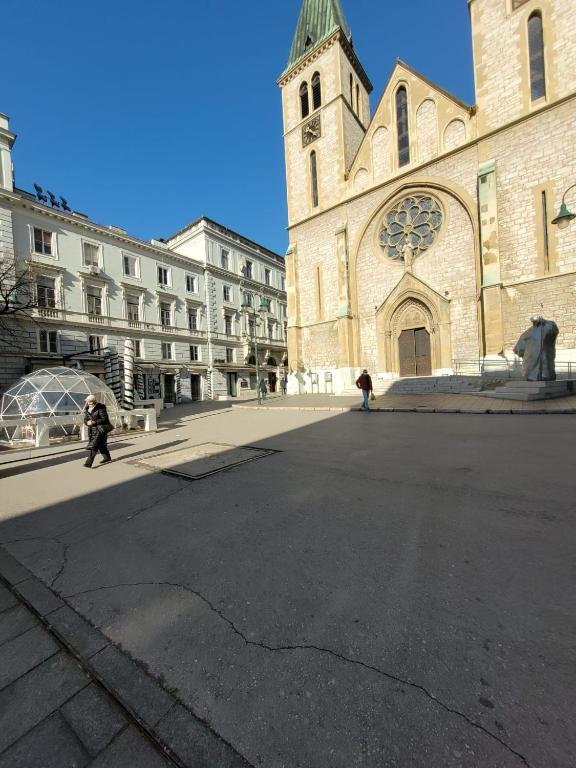 una grande chiesa con torre dell'orologio e un edificio di Minderluk 1 a Sarajevo