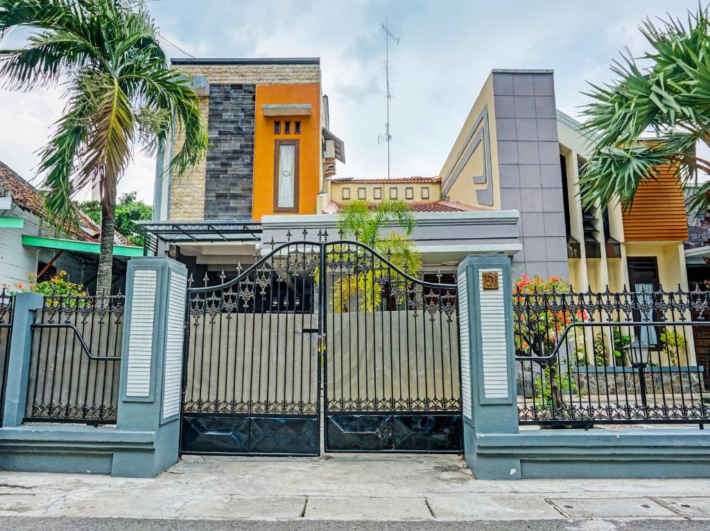 um portão em frente a uma casa com palmeiras em OYO Life 91814 Griya Asoka Syariah em Bojonegoro