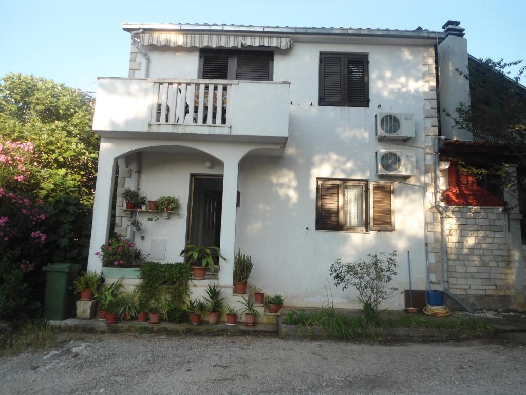 a white house with a balcony and potted plants at Apartment Novaković in Mirce