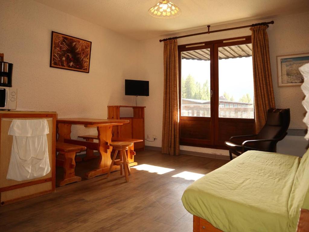une chambre avec un lit, un bureau et une table dans l'établissement Studio 6 pers, sud, centre station, balcon, accès pistes - FR-1-322-133, aux Orres