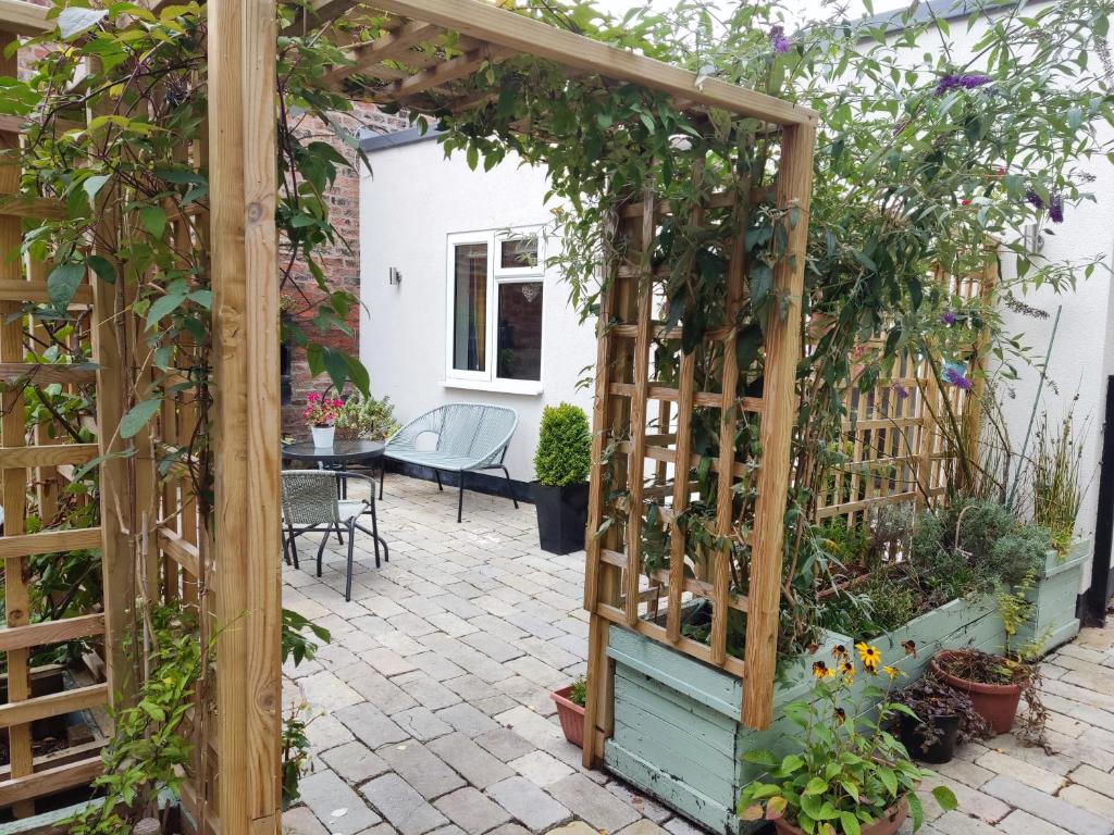 a garden pergola with plants and a table at Little Ings, Modern, idyllic hideaway in Yorkshire market town in Easingwold