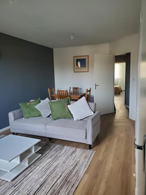 a living room with a white couch and green pillows at Appartement moderne et équipé in LʼIsle-Jourdain