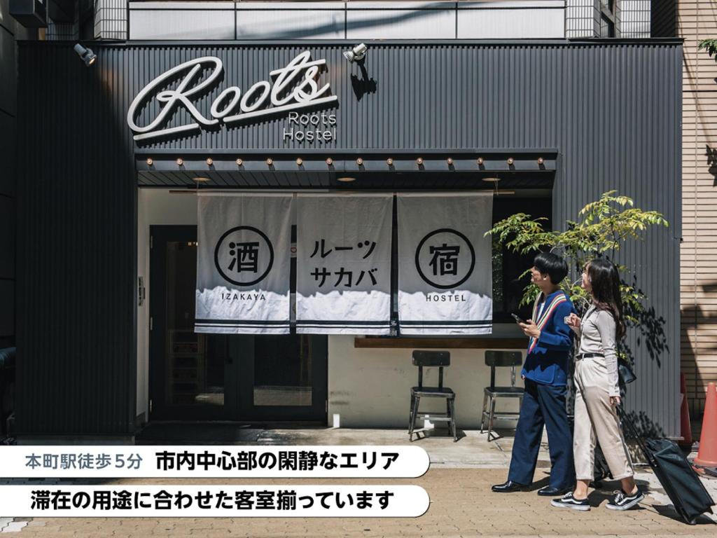 two people standing in front of a restaurant at Roots Hostel in Osaka
