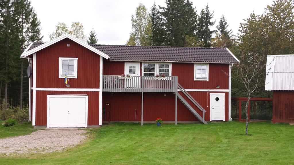 una casa roja con terraza y garaje en Fjättramåla Apartment, en Fagereke