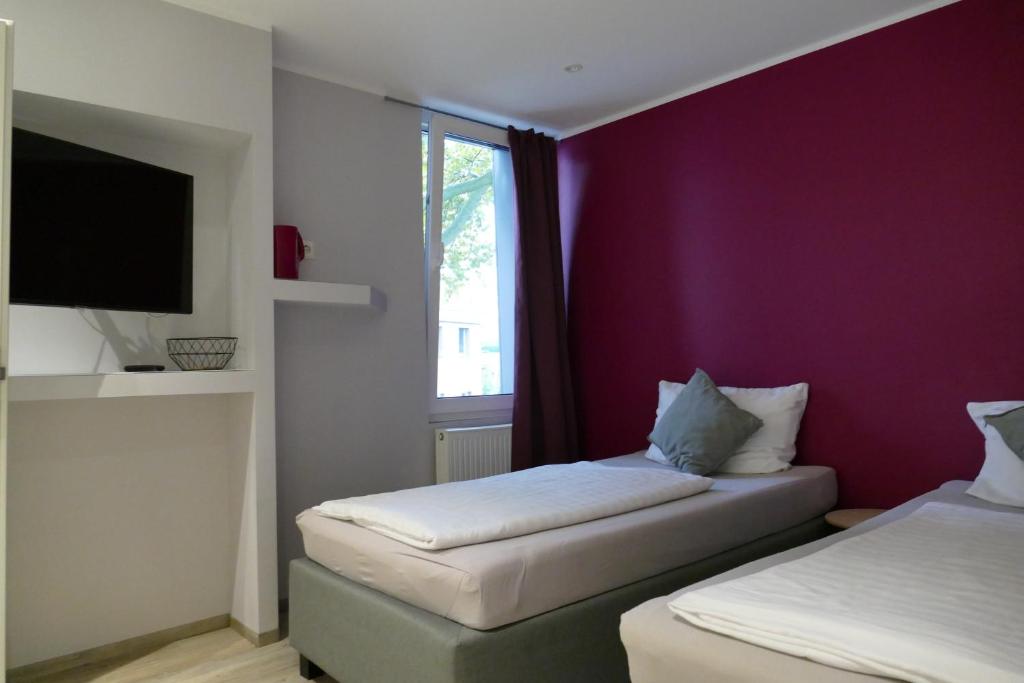1 Schlafzimmer mit 2 Betten und einer lila Wand in der Unterkunft Pension Sölde in Dortmund