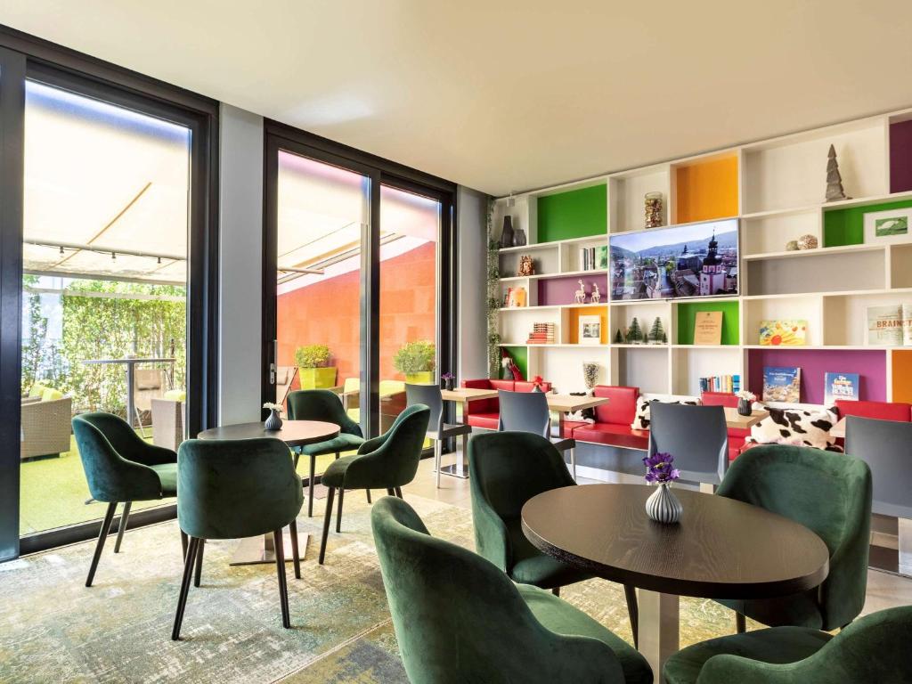 ibis Styles Karlsruhe Ettlingen في إيتلينغن: غرفة انتظار مع طاولات وكراسي ونوافذ