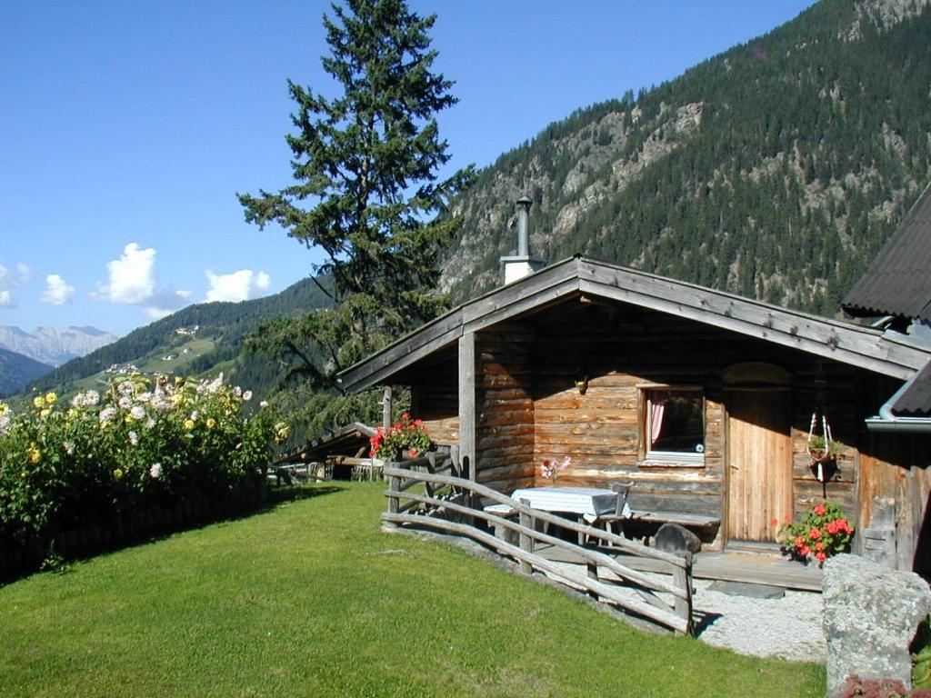 ein Blockhaus auf einem Feld mit Bergen im Hintergrund in der Unterkunft Berghütte Graslehn in Jerzens
