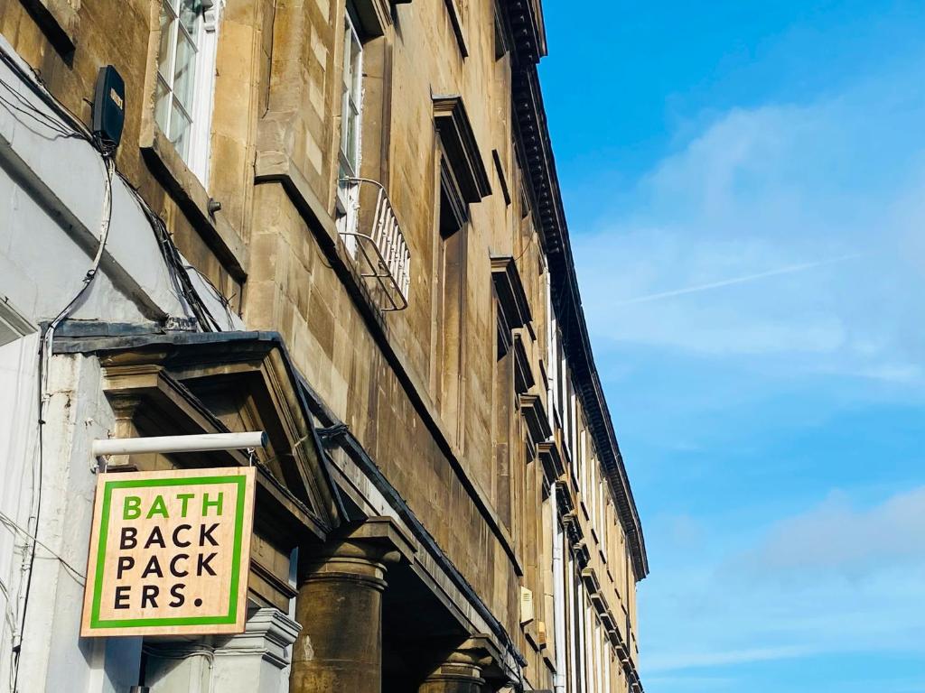 Una señal en el lado de un edificio que dice "devolución de la fe" en Bath Backpackers, en Bath