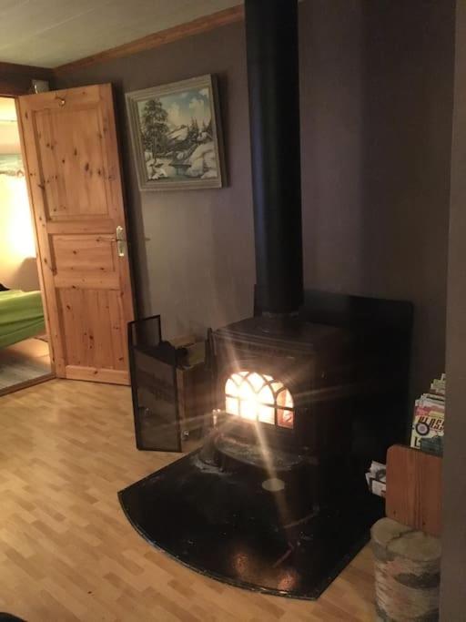 a fireplace in a living room with a stove at StugaNäraKungsberget - mysig stuga med kamin, grillkåta och vedbastu in Ockelbo