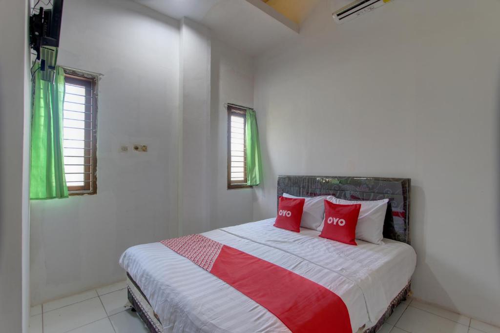 - une chambre blanche avec un lit et des oreillers rouges dans l'établissement Capital O 91690 Moza Guest House, à Klaten