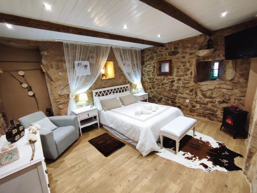 1 dormitorio con 1 cama grande y pared de piedra en A Cuadriña, en Mazaricos
