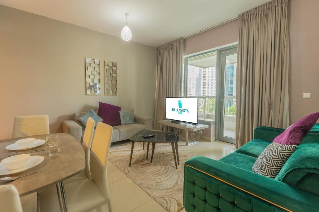 un salon avec un canapé vert et une table dans l'établissement BellaVista - Exuberant - 1BR - 29 Boulevard - Fountain Views, à Dubaï