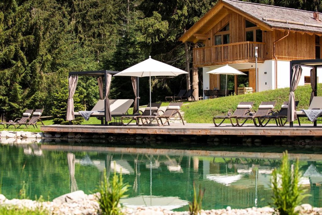 a pool with chairs and umbrellas next to a house at Lerchpeuntgut Alpenfreud Chalets in Tamsweg