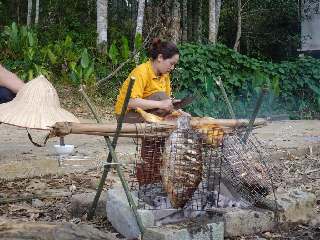 a woman is cooking food in a net at Vĩ Homestay in Lao Cai