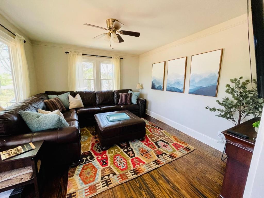 a living room with a leather couch and a ceiling fan at Bountyland Cottage - Lake Keowee - Mountains - Clemson University in Seneca