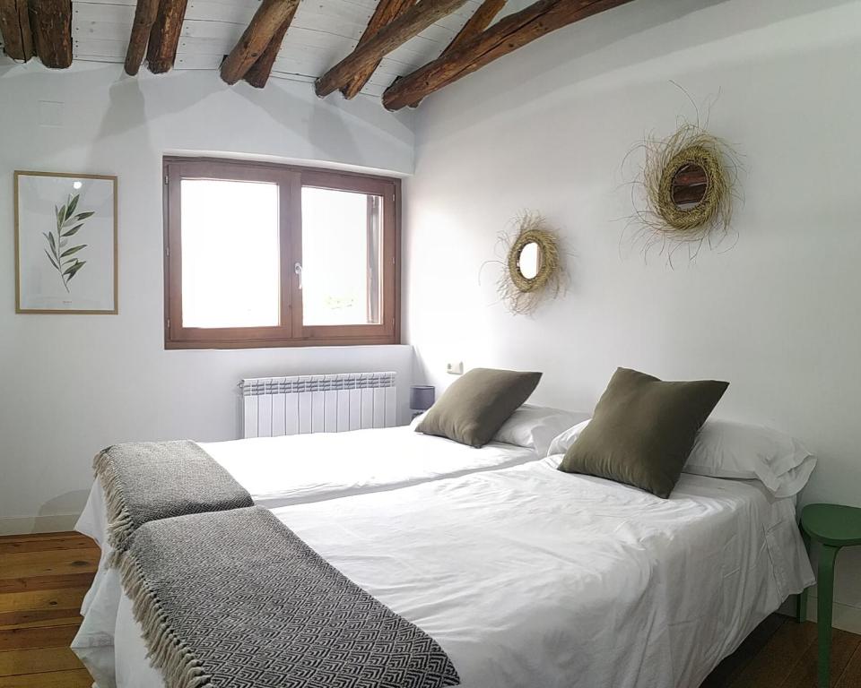 a bedroom with a large bed with white sheets and a window at Casa Alejandra in Murchante