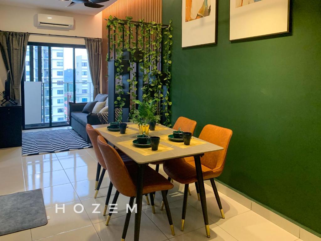 a dining room table with chairs and a green wall at 2BR2B Hozem KL1807 Apartment Kepong in Kuala Lumpur