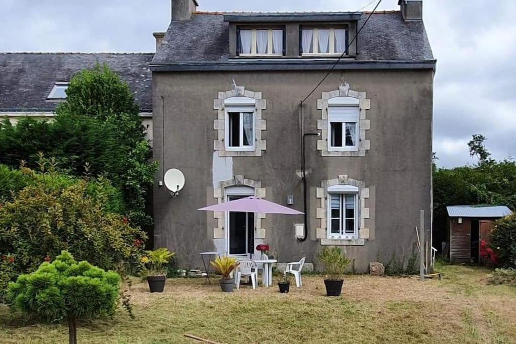 a house with a table and an umbrella in front of it at Studio entre Clohars Carnoet et Doelan in Clohars-Carnoët