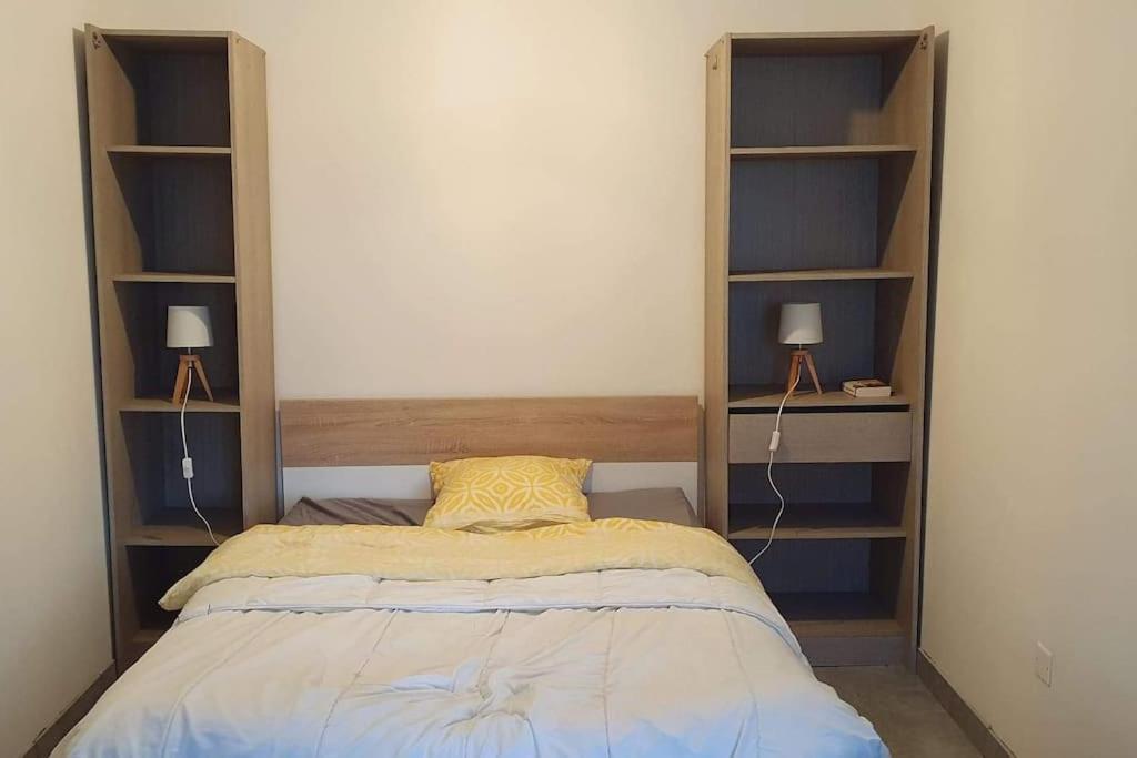 a small bedroom with a bed and shelves at Studio entre Clohars Carnoet et Doelan in Clohars-Carnoët